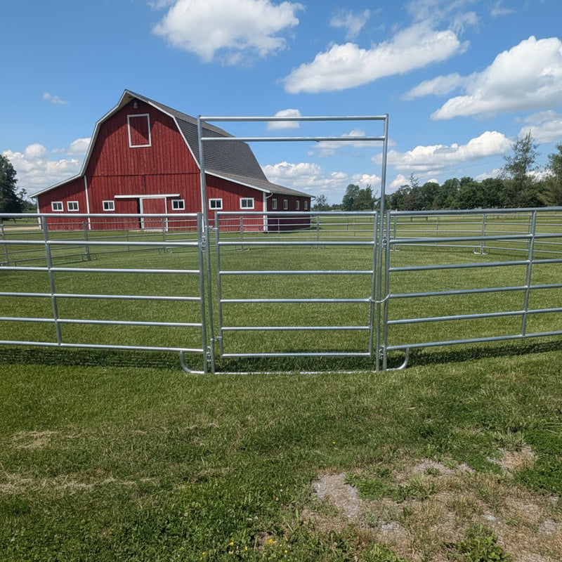 Metal livestock fence in a grassy field with a blue sky and clouds.
