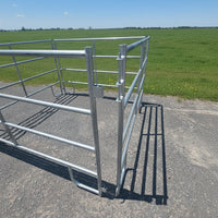 Metal livestock gate on a paved surface with trees and power lines in the background